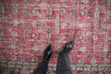 Distressed cherry red vintage Sparta carpet, storied texture, scrolling vinery and palmettes.