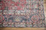 Distressed Sparta rug corner, showcasing cherry red vinery, navy blue palmettes, and time-softened floral borders.