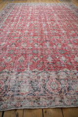 Distressed Sparta carpet's floral main border and cherry red field with time-softened blue tones.