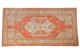 Distressed Oushak carpet with oversized serrated medallion, leaves, and vines in rust, sand, blue.