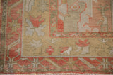 Vintage distressed Oushak carpet corner, faded brick red serrated leaf motif on sand.