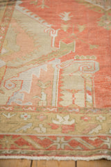 Detail of a distressed vintage Oushak carpet, showing faded rust, beige serrated motifs, and low pile.