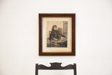 19th century etching depicting a girl weaving, set in an intricately carved dark wooden frame.