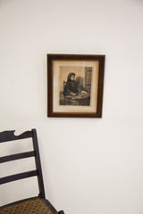 Antique etching with dark carved frame hanging on a white wall.