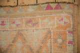 A Kurd rug's stylized cartouche border with pinwheel motifs in faded orange and magenta.
