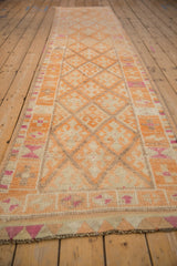 Long perspective view of a vintage Kurd runner with a faded tangerine diamond lattice pattern.