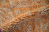 A soft fold reveals the hand-knotted short pile of a distressed tangerine rug.