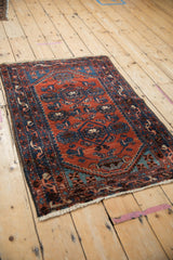 Vintage Borchalou rug seen from an angle, featuring geometric arabesques in rust red and sapphire blue.