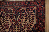 Antique Mohajeran Sarouk rug corner with ivory field, ruby red floral vinery, and serpent border.