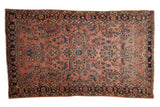 Antique Sarouk rug features a dusty rose field with dense floral sprays and navy borders.
