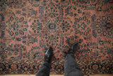 Antique Persian Sarouk rug with faded raspberry field, dense floral sprays, and visible wear.