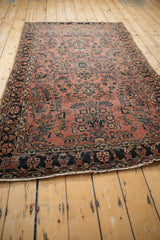 Antique Sarouk rug: navy blue meandering vine border, dusty red floral field, tattered.