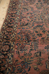 Intricate meandering vine border and floral sprays on the dusty raspberry field of this antique Sarouk rug.