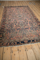 Antique Sarouk rug end, featuring tattered fringe, navy floral border, and dusty pale raspberry field.
