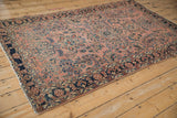 Antique Sarouk rug's tattered fringe and side selvage detail on dark navy floral border.
