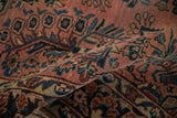 Antique Sarouk rug's textured dusty rose field, navy floral sprays, and meandering vine details.