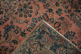 Dusty red Sarouk rug pile, faded navy floral motifs, showing exposed foundation and tattered fringe.