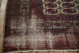 Low pile, tattered fringe, and geometric borders on vintage Afghani rug in red, beige.
