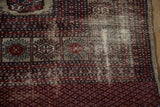 Visible foundation and geometric guls in cherry red, navy on vintage Bokhara rug.