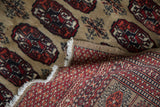 Hand-knotted Afghani Bokhara rug: detailed reverse foundation, pile, and tattered fringe.