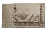 Vintage distressed Oushak rug with a stepped center medallion in chocolate brown on a faded sandalwood ground.