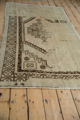 Angled view of a distressed Oushak rug highlighting its worn texture and chocolate brown geometric patterns.