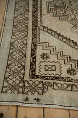 Worn pile and geometric border of a distressed Oushak rug in sandalwood and chocolate brown.