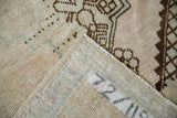 Corner of a distressed Oushak rug showing the woven back, painted numbers, and low pile.