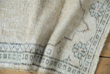 Worn ivory pile of a distressed Oushak with geometric pale jade and brown border.