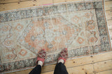 Distressed vintage Oushak rug corner, showing dark chocolate brown geometric border and faded terracotta patterns.