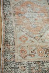 Distressed hand-knotted Oushak rug corner with pale rust, ivory, and brown geometric patterns.