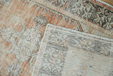 Folded corner of vintage distressed Oushak rug shows pile, exposed foundation, and intact selvage.
