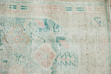 Distressed Oushak rug pile texture with faded ivory, beige, green, and rose hues.
