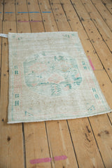 Distressed Oushak rug corner, revealing low pile, ivory tones, and muted jade green.