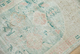 Vintage distressed Oushak rug close-up, showing faded ivory, rose, and jade green knot heads.
