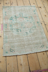 Distressed vintage Oushak rug showing faded jade green, rose patterns, and visible foundation wear.