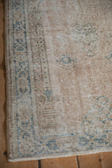 Distressed vintage Sparta rug showing worn knot heads, intact side selvage, and muted blue patterns.