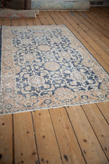 Distressed texture highlighting navy blue and pale coral pomegranate motifs on a vintage Sparta rug.