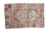 Distressed vintage Oushak rug with a floral medallion, a heavily worn pile, and decorative pops of pink and orange.