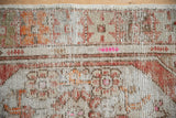 Textural detail of a distressed Oushak rug with faded floral patterns and visible woven foundation.