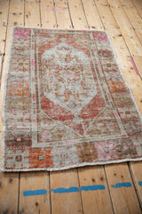 Low angle view of a distressed Oushak rug with fuchsia, sand, and burnt orange accents.