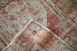 Folded corner of a distressed Oushak rug reveals the hand-knotted construction and worn texture.