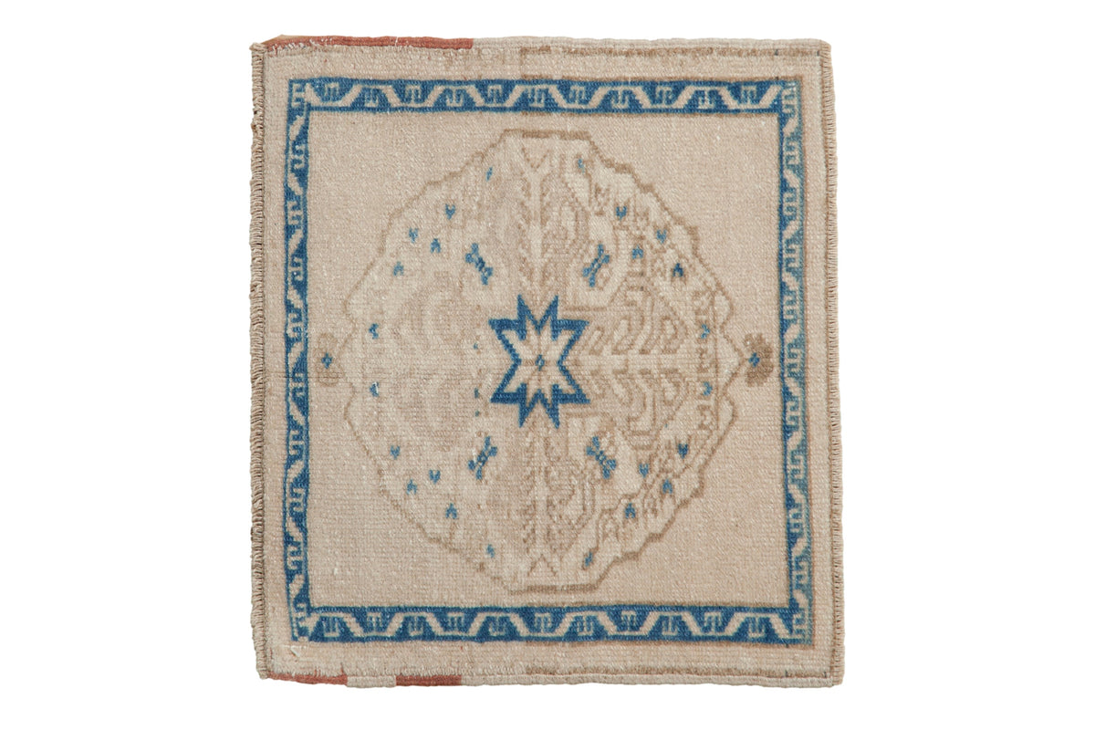 Vintage distressed Oushak square mat with a sapphire blue starburst medallion on a worn ivory and beige field.