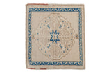 Vintage distressed Oushak square mat with a sapphire blue starburst medallion on a worn ivory and beige field.