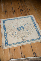 High-angle view of the square Oushak mat's decorative starburst medallion and distressed texture.