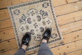 A small square vintage Oushak rug with stylized floral designs shown in-use to convey scale.