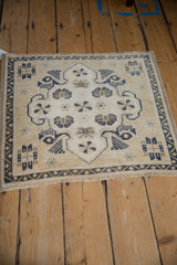 Angled perspective of a square Oushak rug showing its distressed texture and geometric navy motifs.