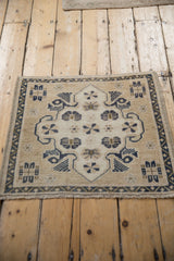 A vintage distressed Turkish Oushak rug with a shield medallion and pinwheel florals on a sand field.