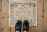 Distressed Oushak rug corner showing cream, pale brown tones, faded geometric border, visible wear.