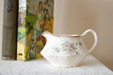 Vintage Homer Laughlin creamer with fluted sides, a pink floral design, and gold rim.